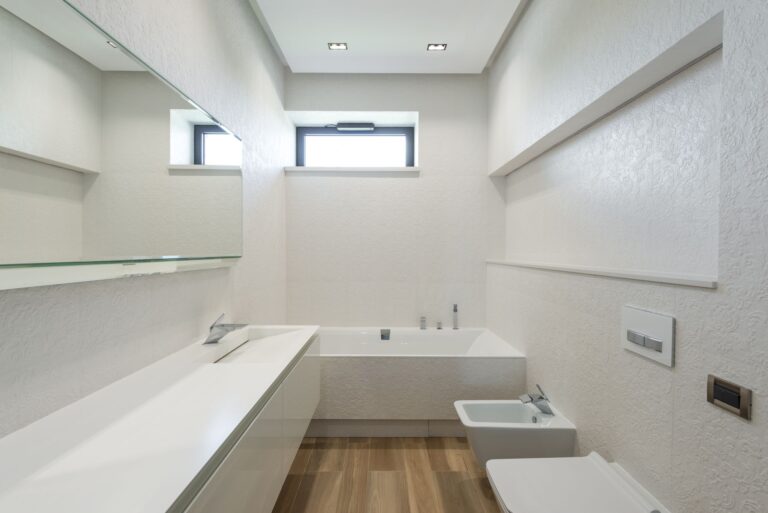 Wide view of a clean modern bathroom with wood floor