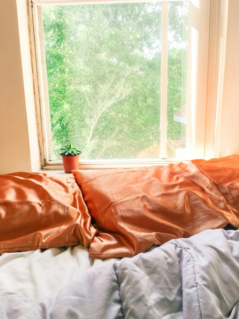 White bed linen with green plant accent in clean bedroom